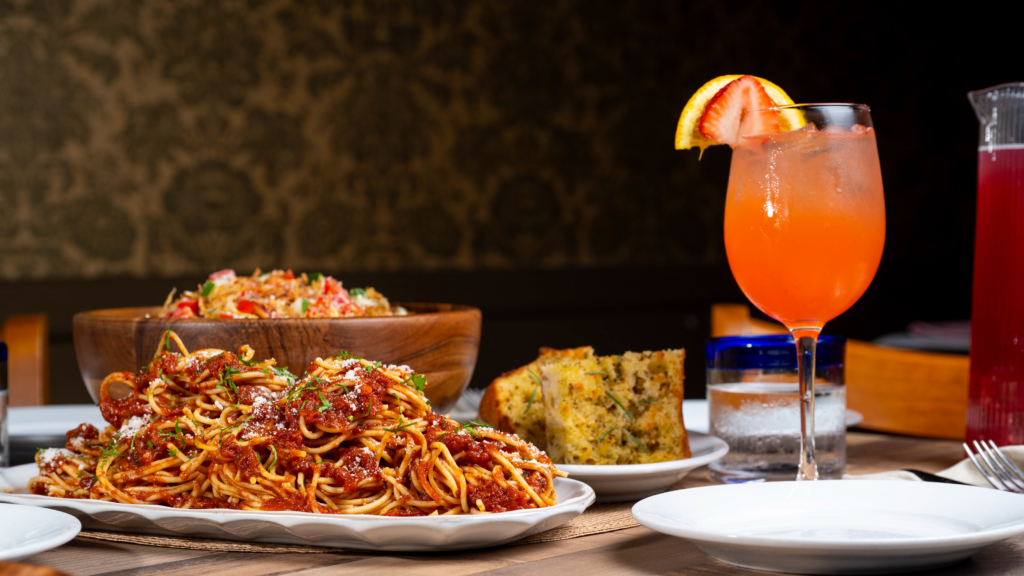 Spaghetti, salad, garlic bread and sangria on a table.
