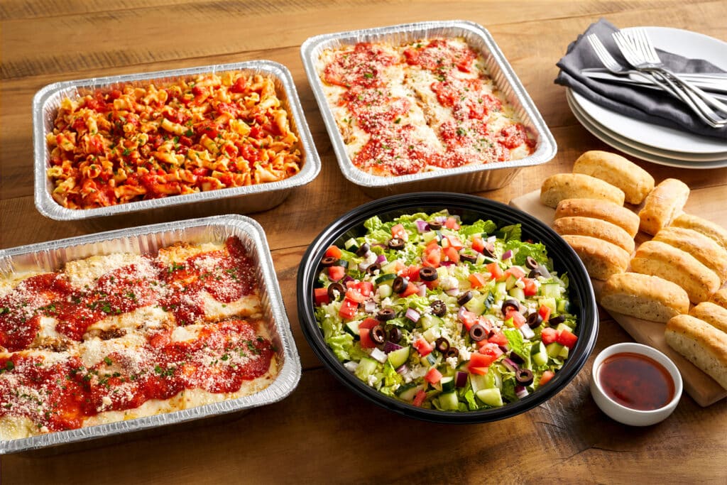 Bravo's catering spread featuring lasagna, chopped salad, bread