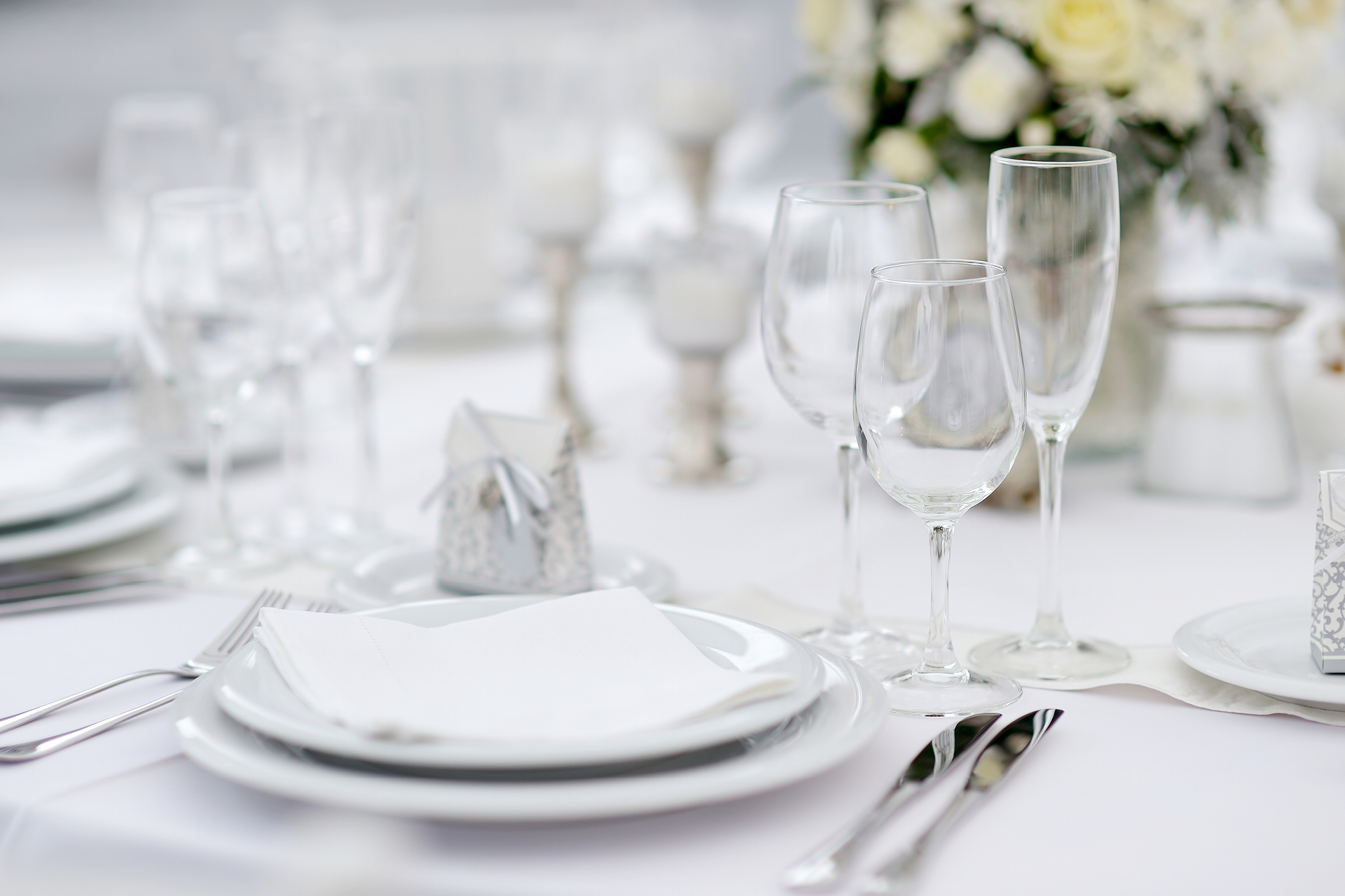 Elegant white table setting with wine glasses, silverware, and floral centerpieces at Bravo Italian Kitchen.